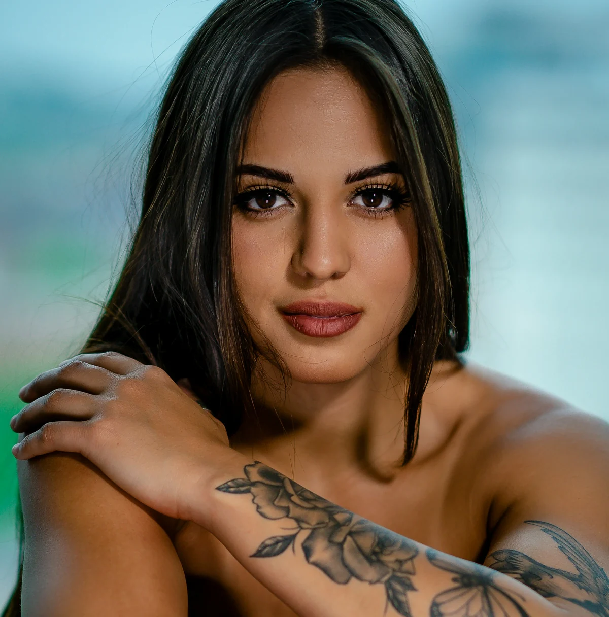 Close editorial portrait of an adult woman with crossed arms and shoulders visible